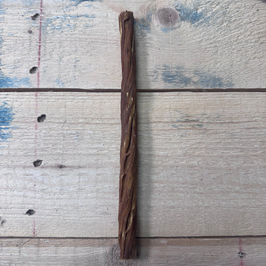 A single 10 inch dried beef tripe twist for dogs on a weathered wood background